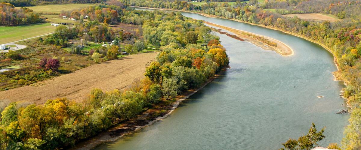 A river winding through a valley with autumn-colored trees and rolling hills in the background.