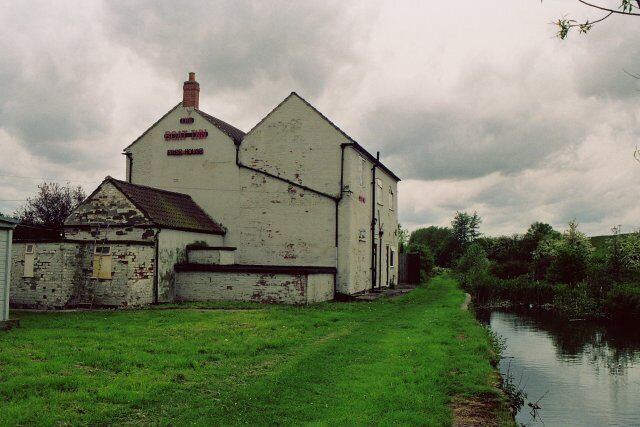 A white building with a sign reading "Grange Farm" by a canal.