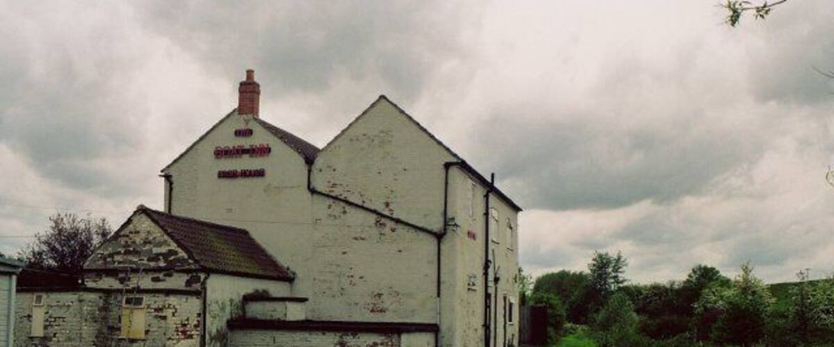 A white building with a sign reading "Grange Farm" by a canal.