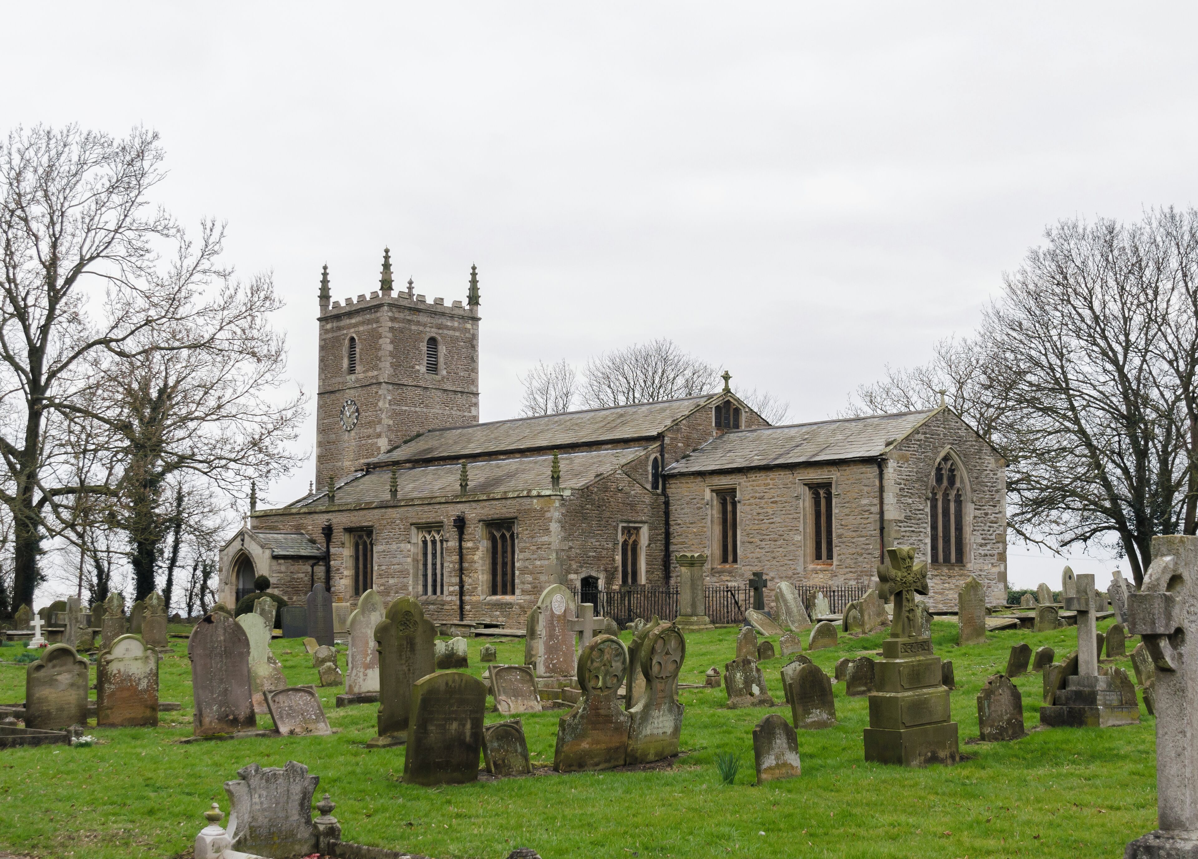 A historic church with a tall tower and a cemetery in the foreground.