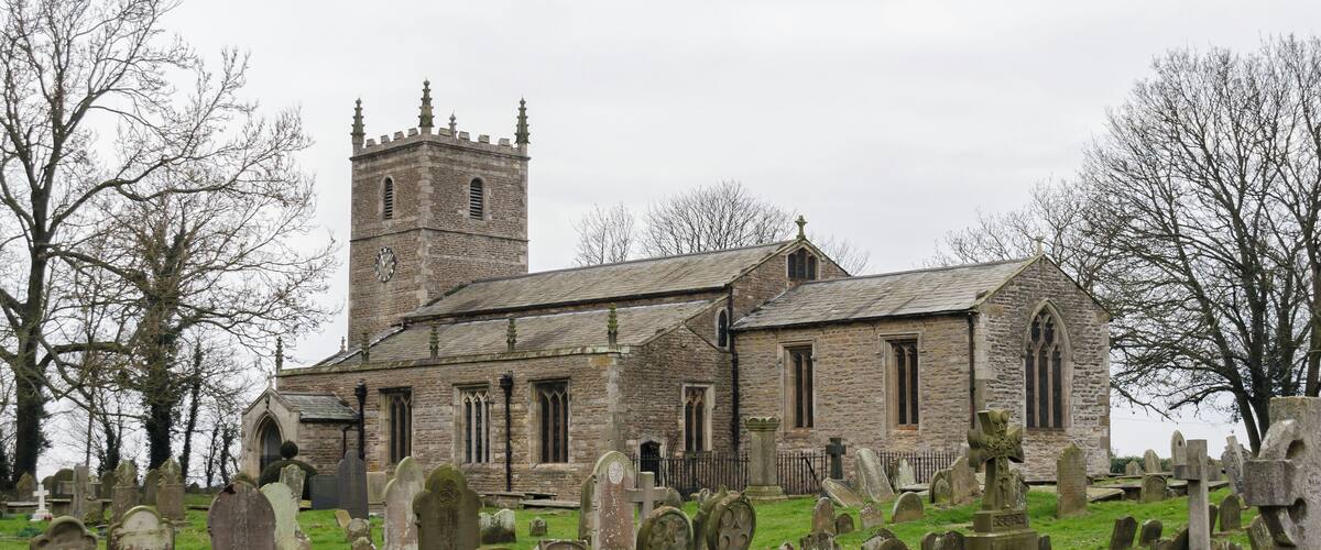 A historic church with a tall tower and a cemetery in the foreground.