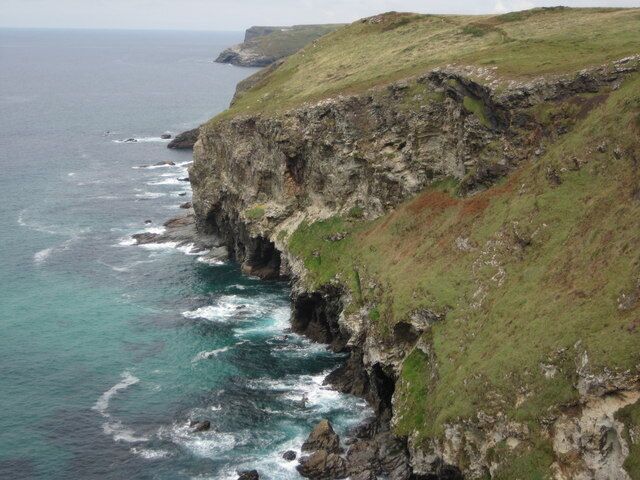 A coastal cliff with waves crashing against it.