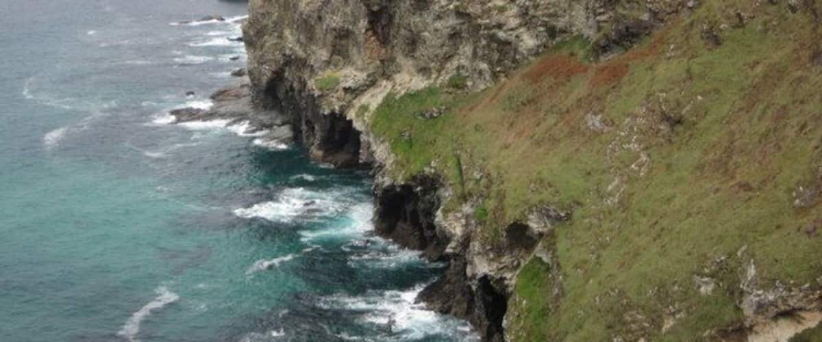 A coastal cliff with waves crashing against it.