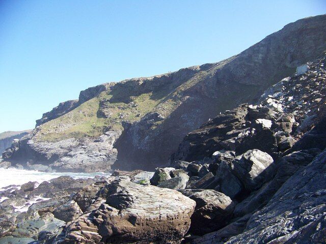 Flat Hole Cave Two walkers on the coastal path look down onto Flat Hole and the large cave (in shadow centre)