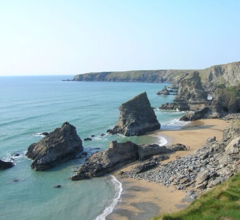 A coastal landscape with rocky formations and a sandy beach.