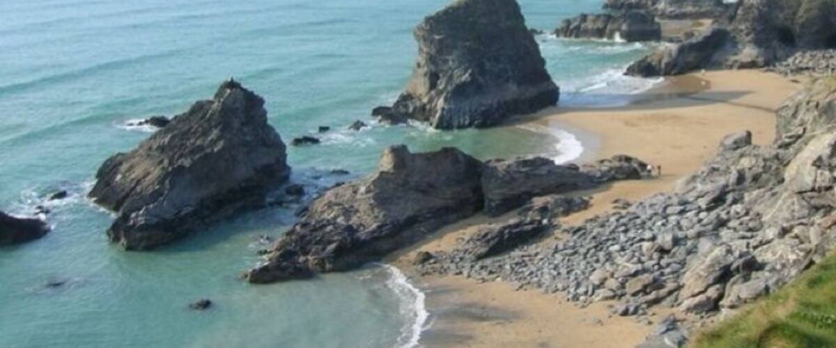 A coastal landscape with rocky formations and a sandy beach.
