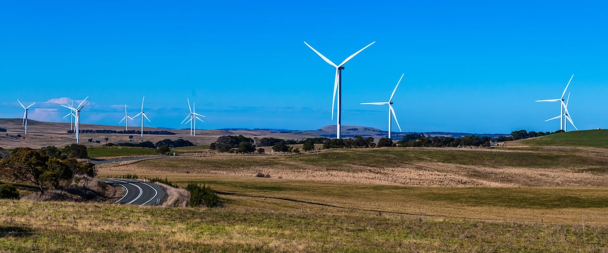 A landscape with multiple wind turbines and a winding road.