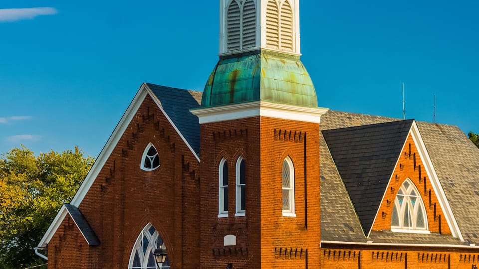 A brick church with a green dome and a steeple.