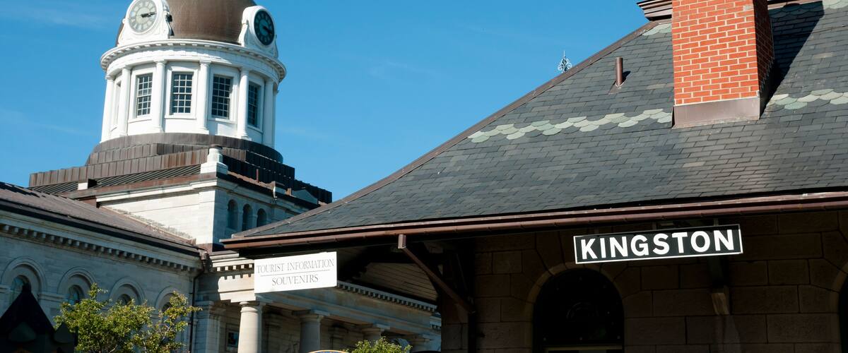A historic building with a clock tower and a sign reading "Kingston Tourist Information."