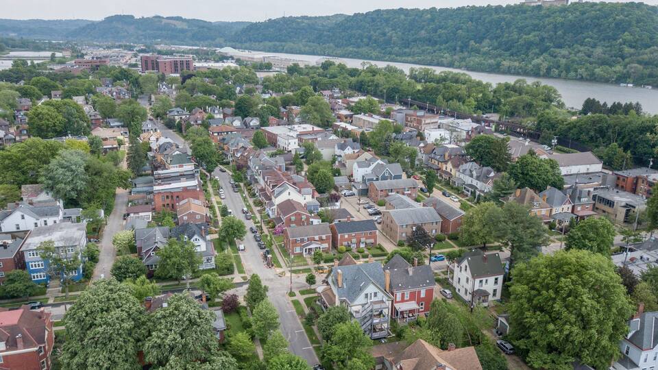 A residential area with houses, trees, and a river in the background.