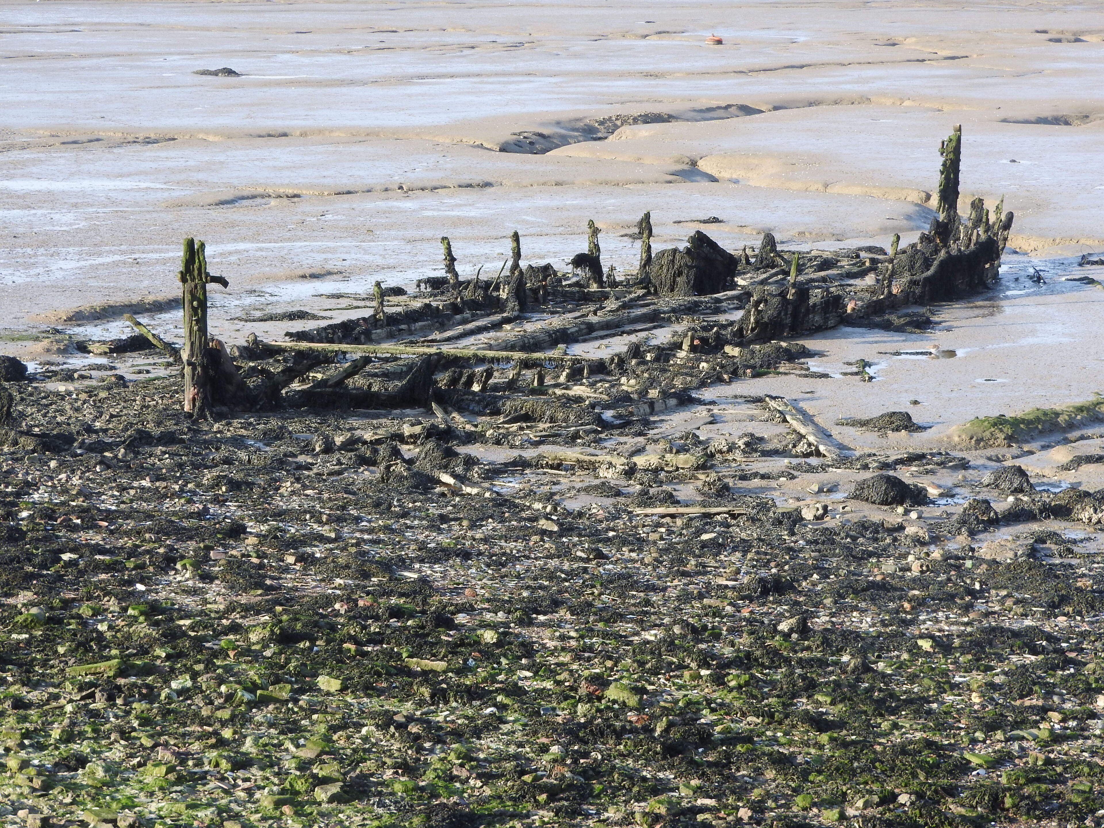 A beach with a large, eroded shipwreck.