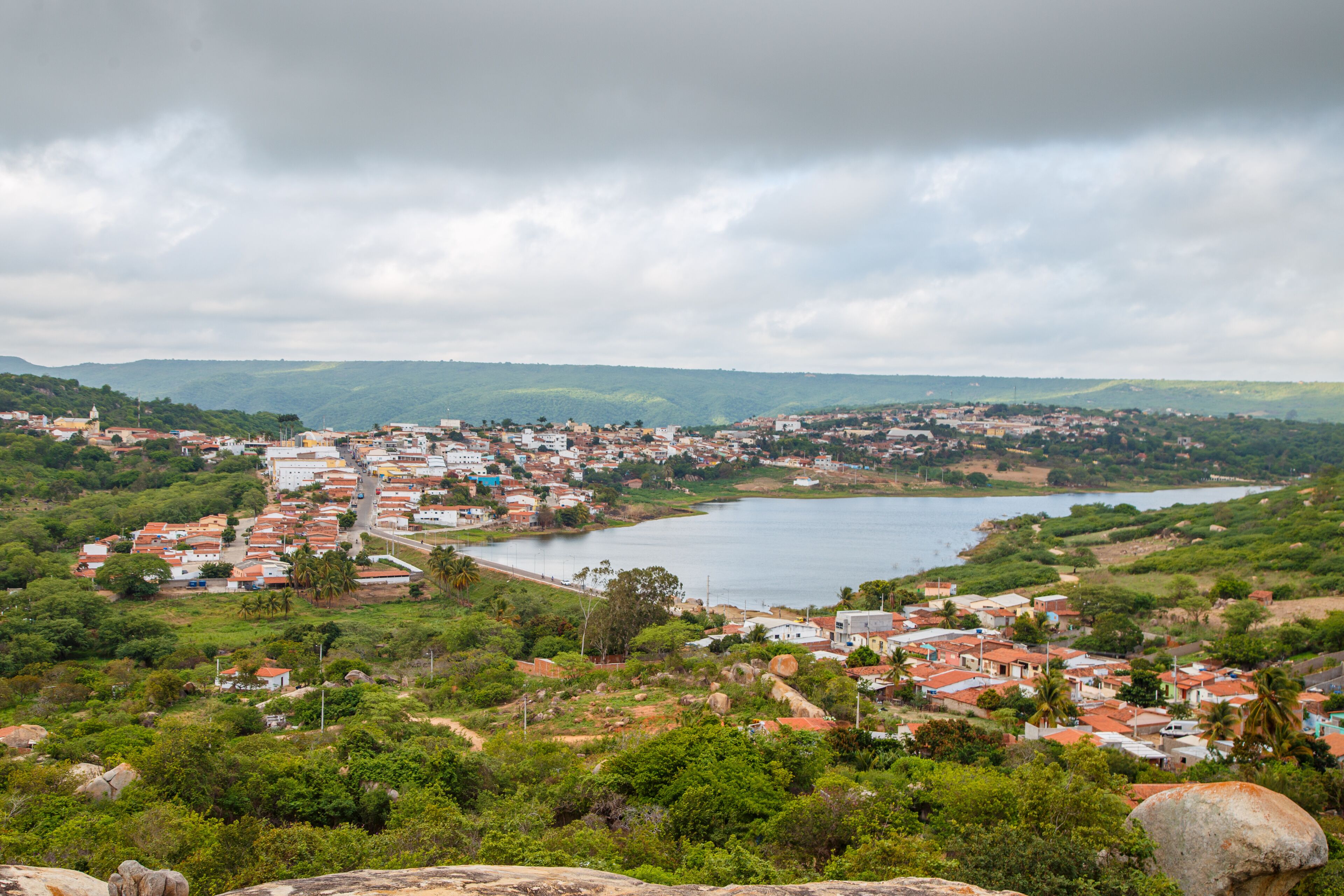 A coastal town with a river, surrounded by hills and greenery.