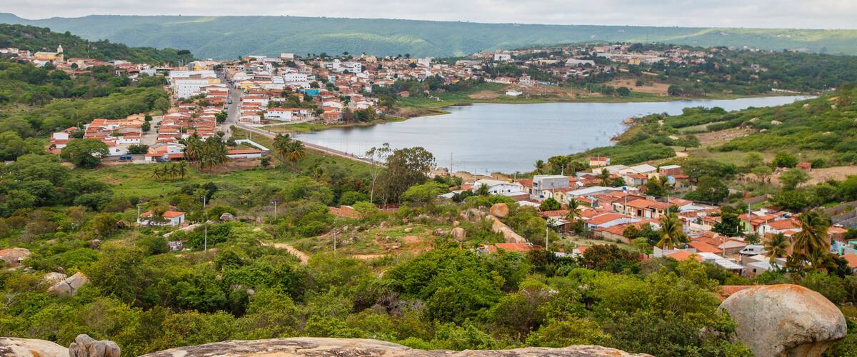 A coastal town with a river, surrounded by hills and greenery.