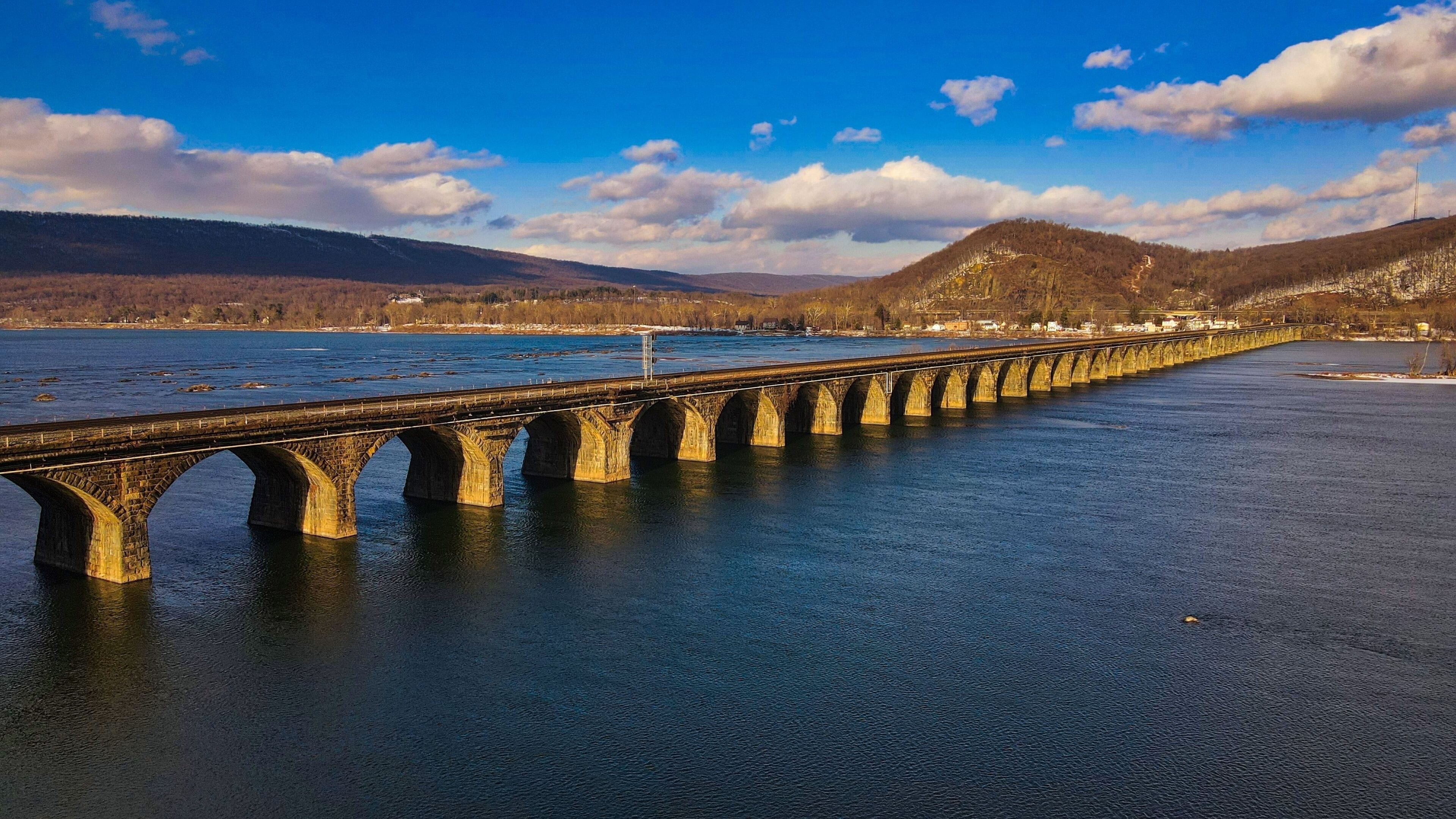 A stone bridge over a river with mountains in the background.