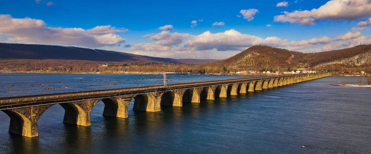 A stone bridge over a river with mountains in the background.