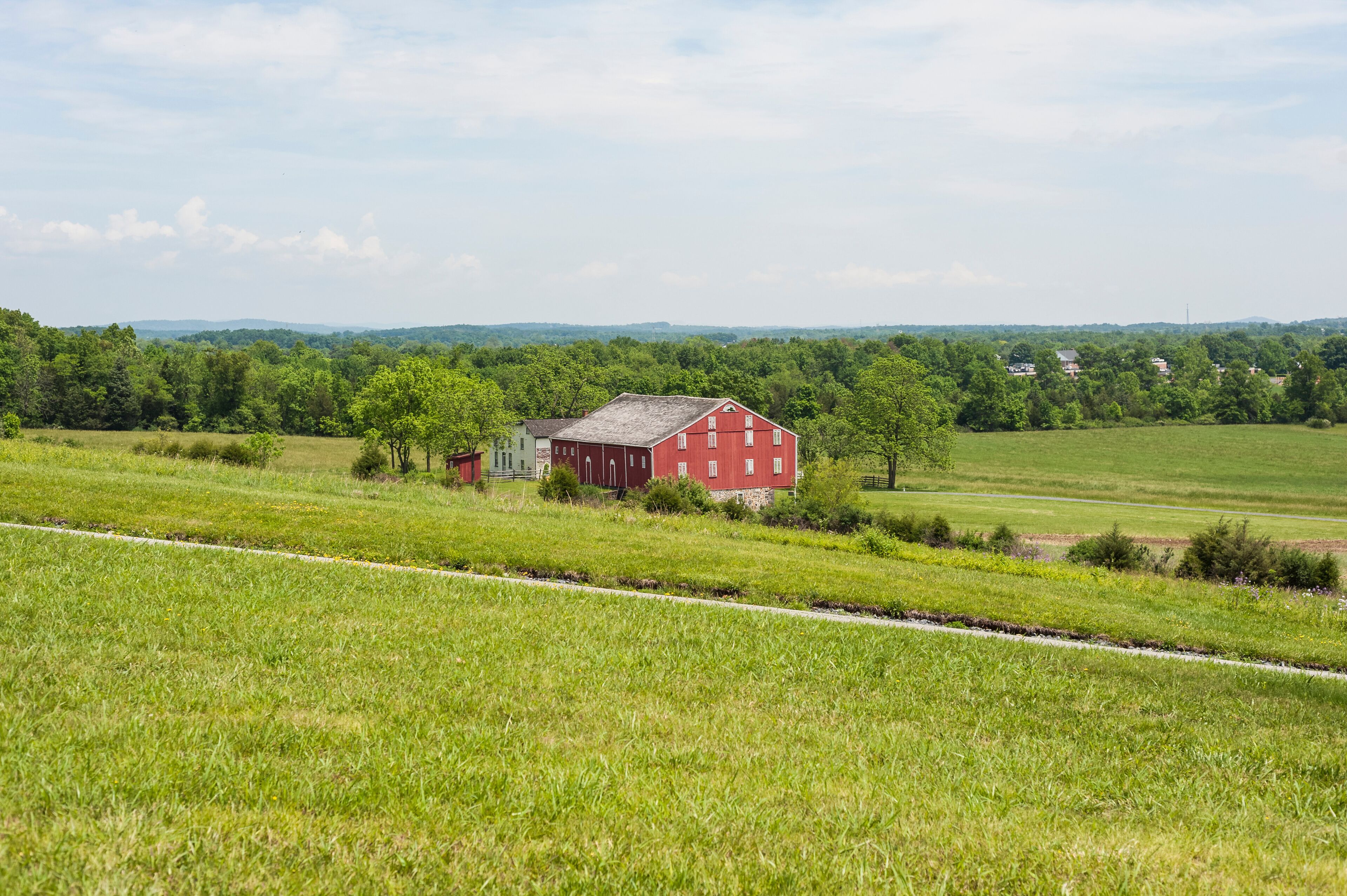 A red barn in a green field with a clear sky.