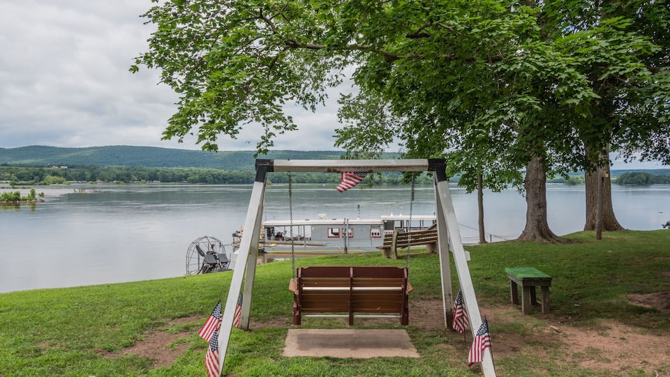 A wooden swing set with American flags, a bench, and a small table by a lake.