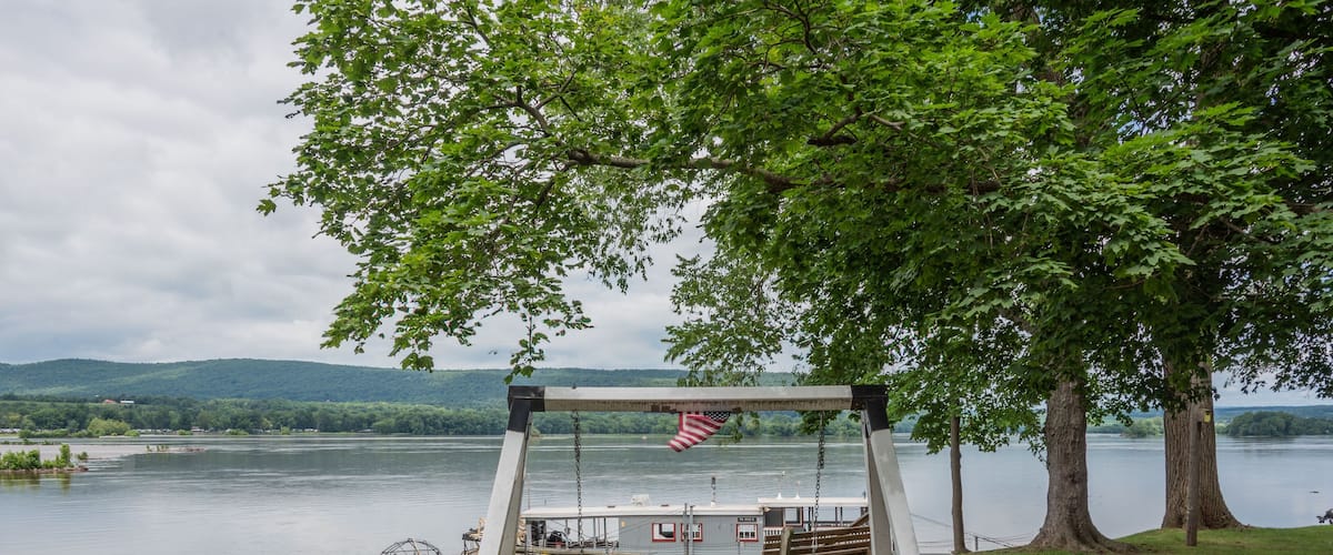 A wooden swing set with American flags, a bench, and a small table by a lake.