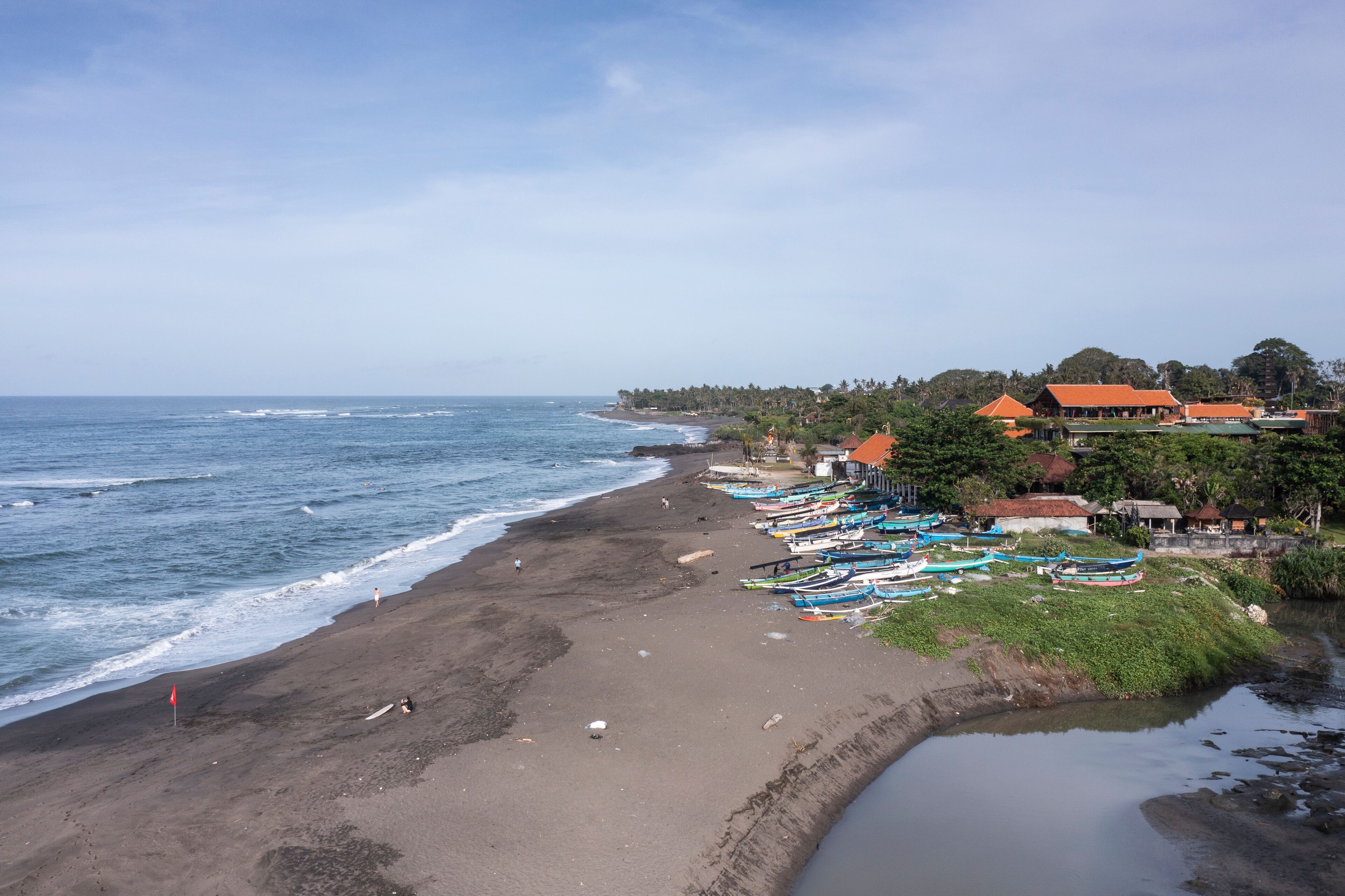 A beach with boats, a sandy shore, and buildings in the background.