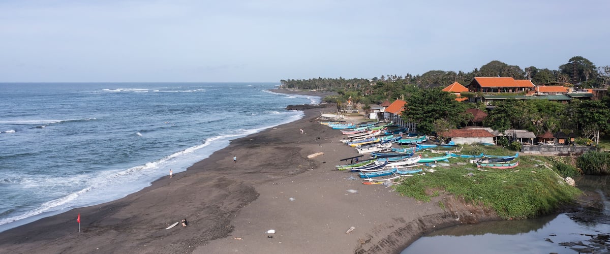 A beach with boats, a sandy shore, and buildings in the background.