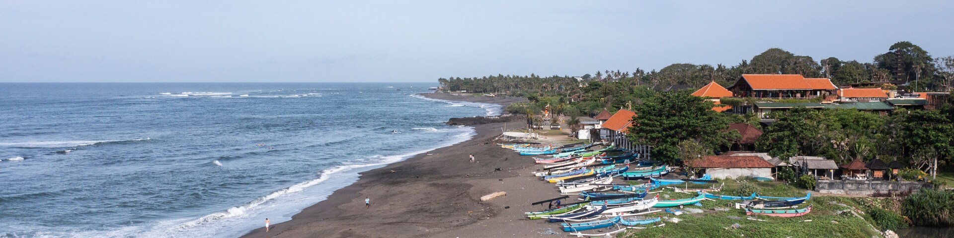 A beach with boats, a sandy shore, and buildings in the background.