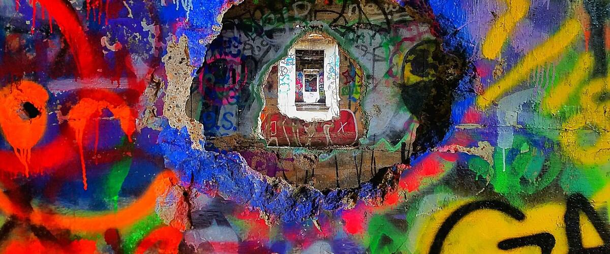 A colorful graffiti mural with a central window and abstract shapes.