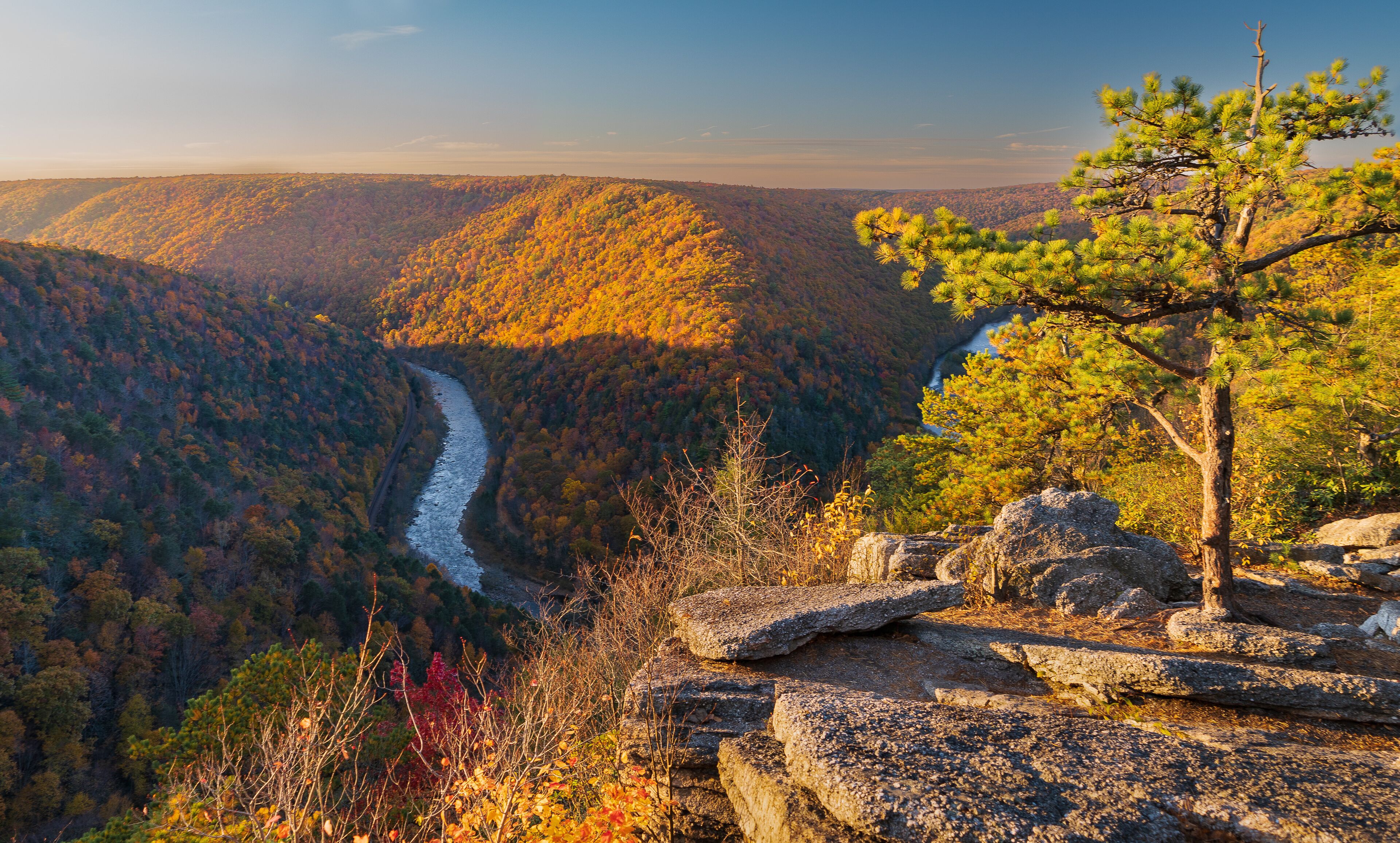 A river winding through a forested valley with autumn foliage.