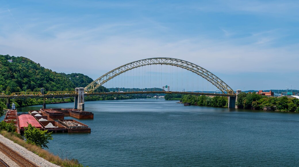 The West End Bridge that spans the Ohio River and connects the north side and the west end in Pittsburgh, Pennsylvania, USA. Several barges and a tugboat are moored to the west end shoreline