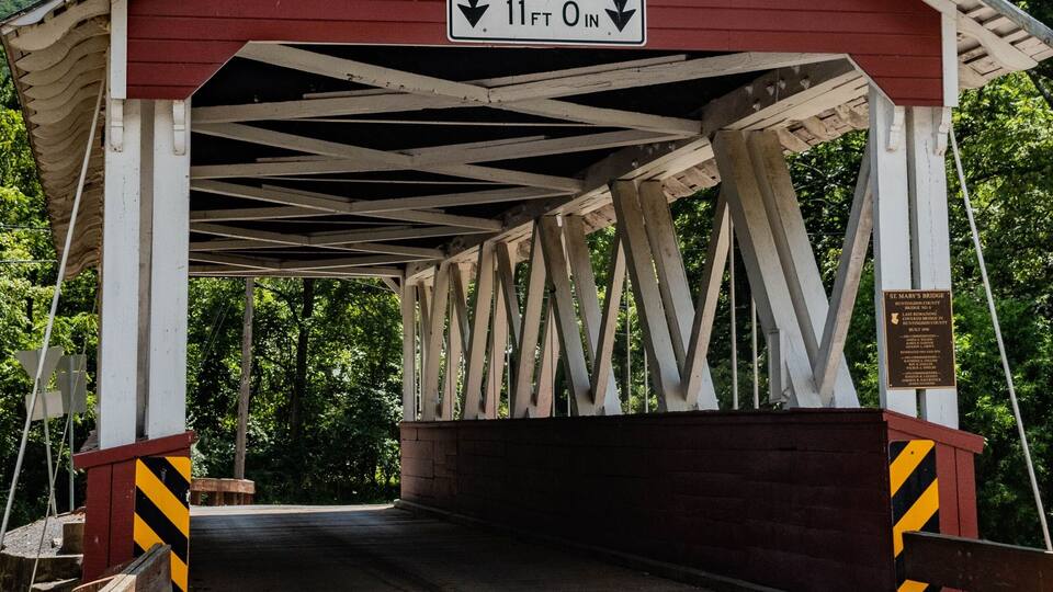 A covered bridge with a sign indicating clearance of 11 feet 0 inches.