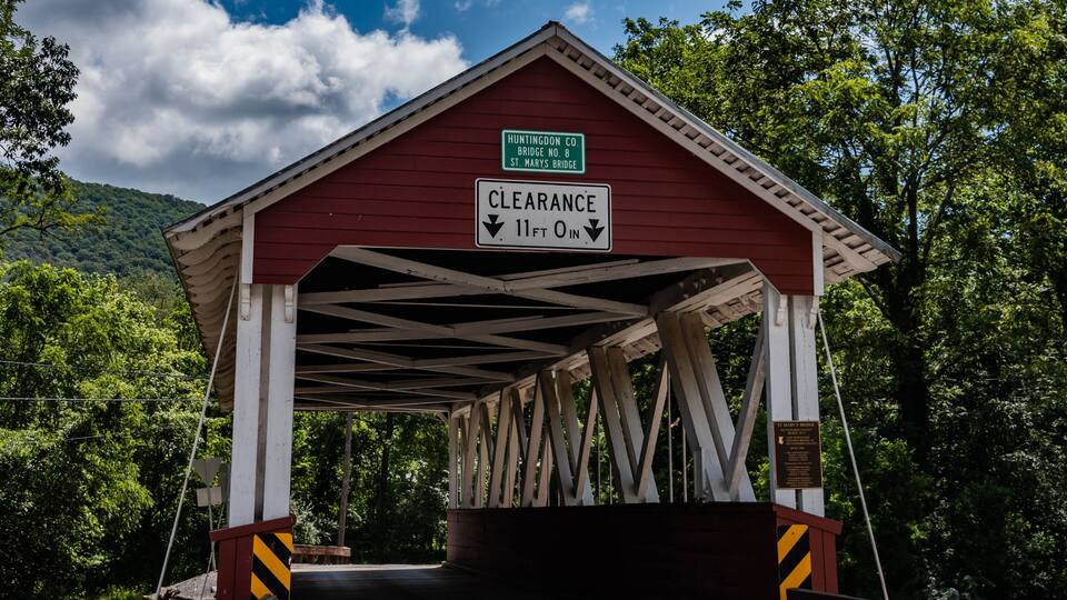 A covered bridge with a clearance sign indicating 11 ft 0 in.