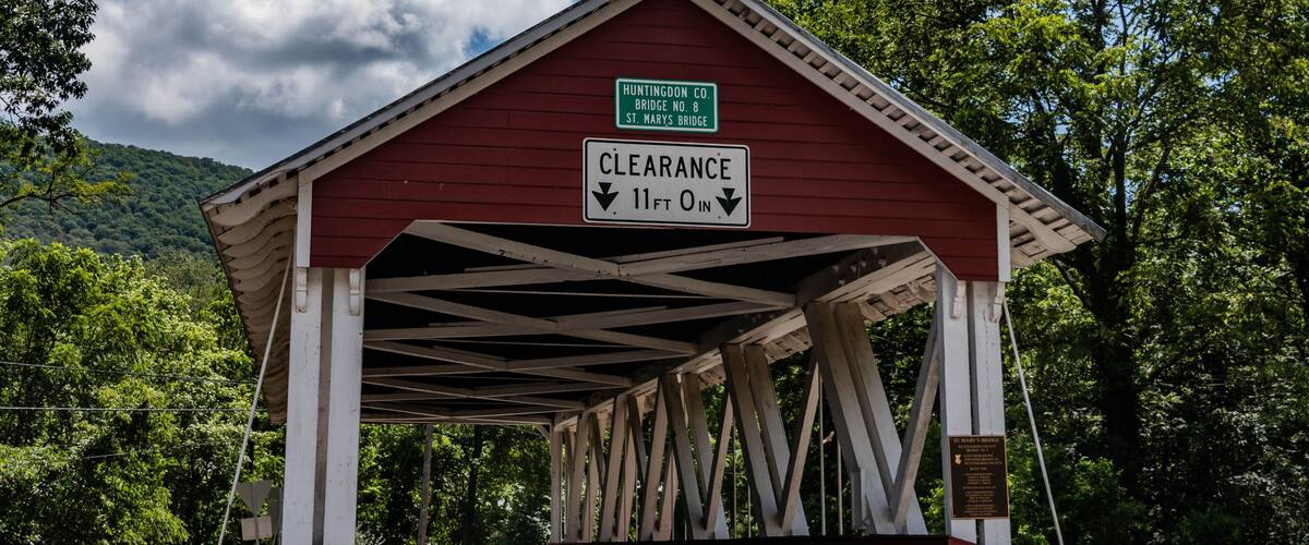 A covered bridge with a clearance sign indicating 11 ft 0 in.