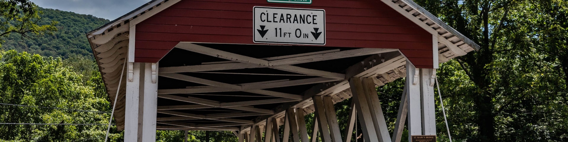 A covered bridge with a clearance sign indicating 11 ft 0 in.
