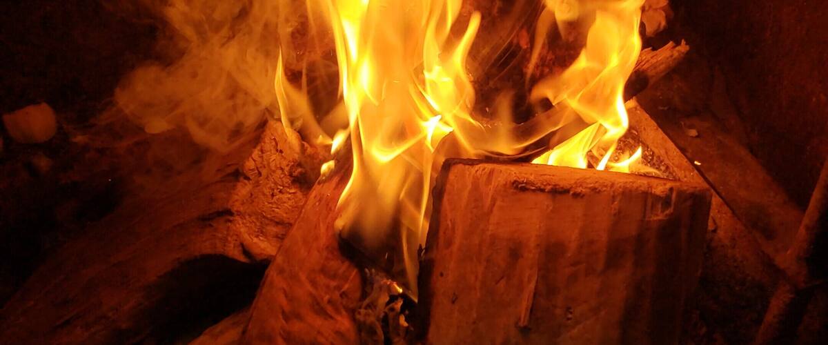 A campfire with flames consuming wood logs.