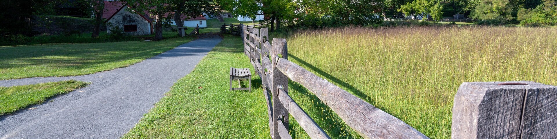 Split rail fence along country gravel road with pasture idyllic country scene