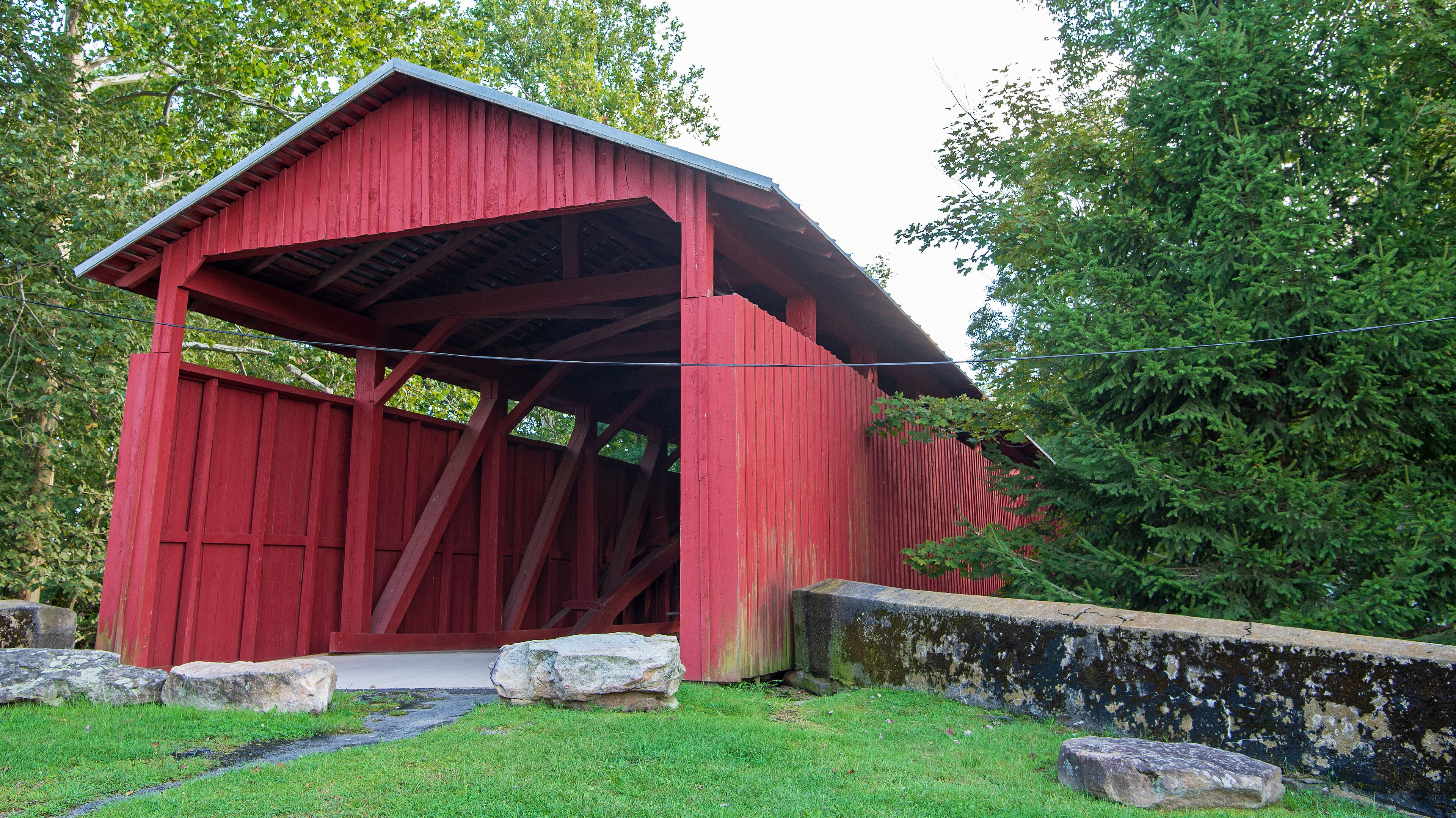 A red covered bridge with stone steps and a stone wall.