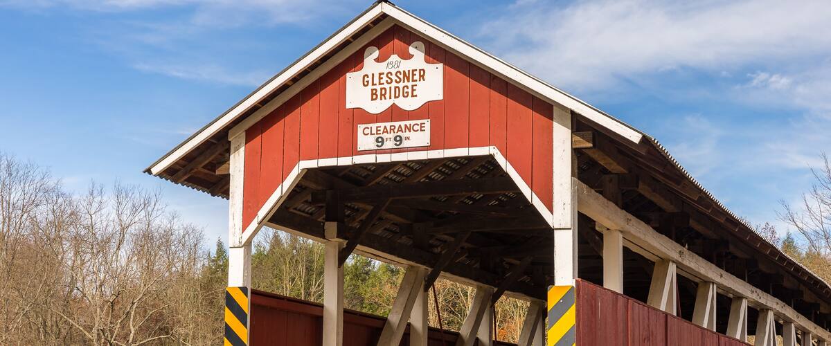 A red covered bridge with a sign reading "Glessner Bridge Clearance 9 ft 9 in."