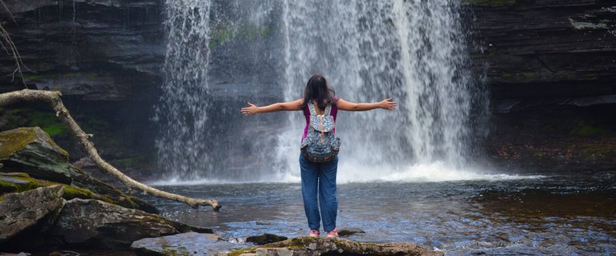 A waterfall with a person standing in front of it.