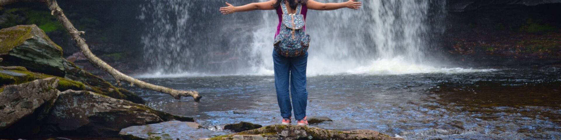 A waterfall with a person standing in front of it.