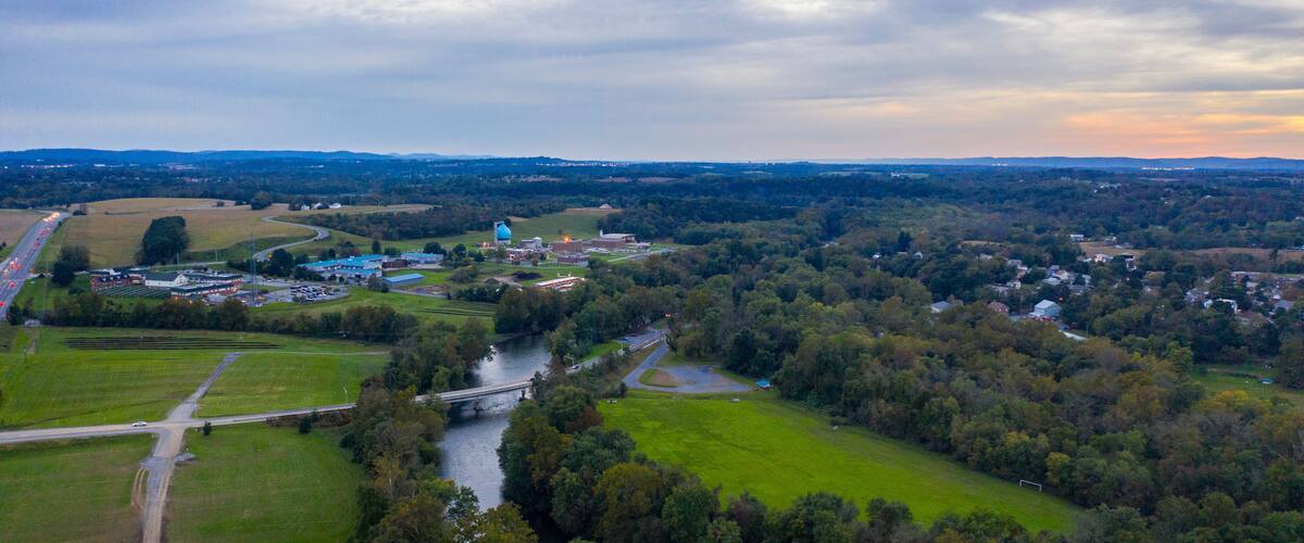 An aerial view of a town with a river, green fields, and industrial buildings.