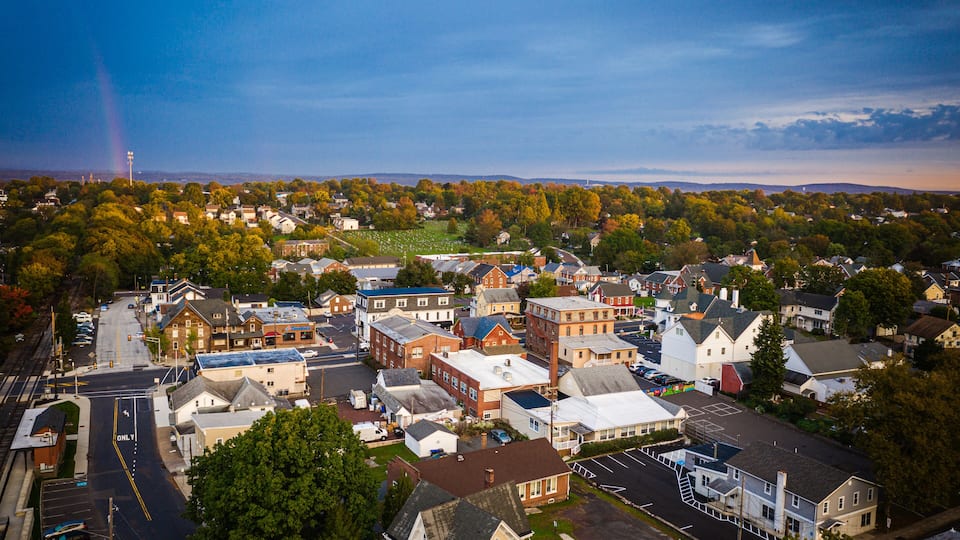 A town with a mix of residential and commercial buildings, a prominent church, and a clear sky.