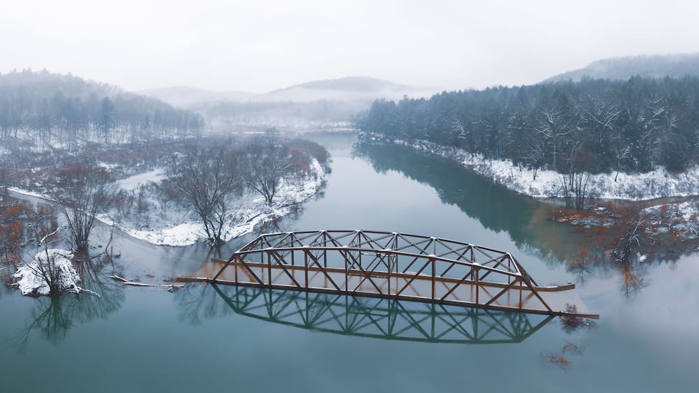 Flooded Bridge in Snowy Mountains from Above