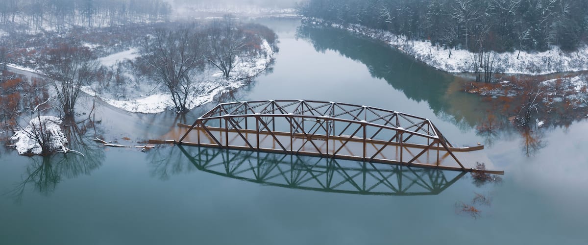 Flooded Bridge in Snowy Mountains from Above