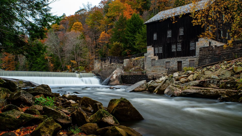 A waterfall, a stone building, and autumn foliage.