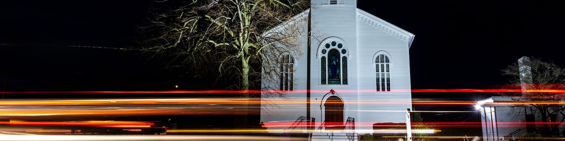 A white church with a pointed steeple at night.