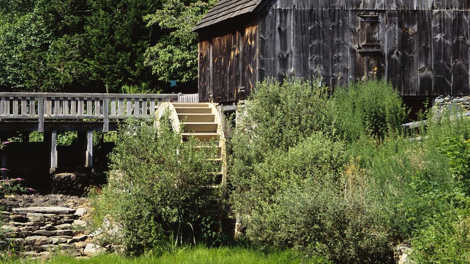 A rustic wooden structure with a wooden bridge and a water wheel.