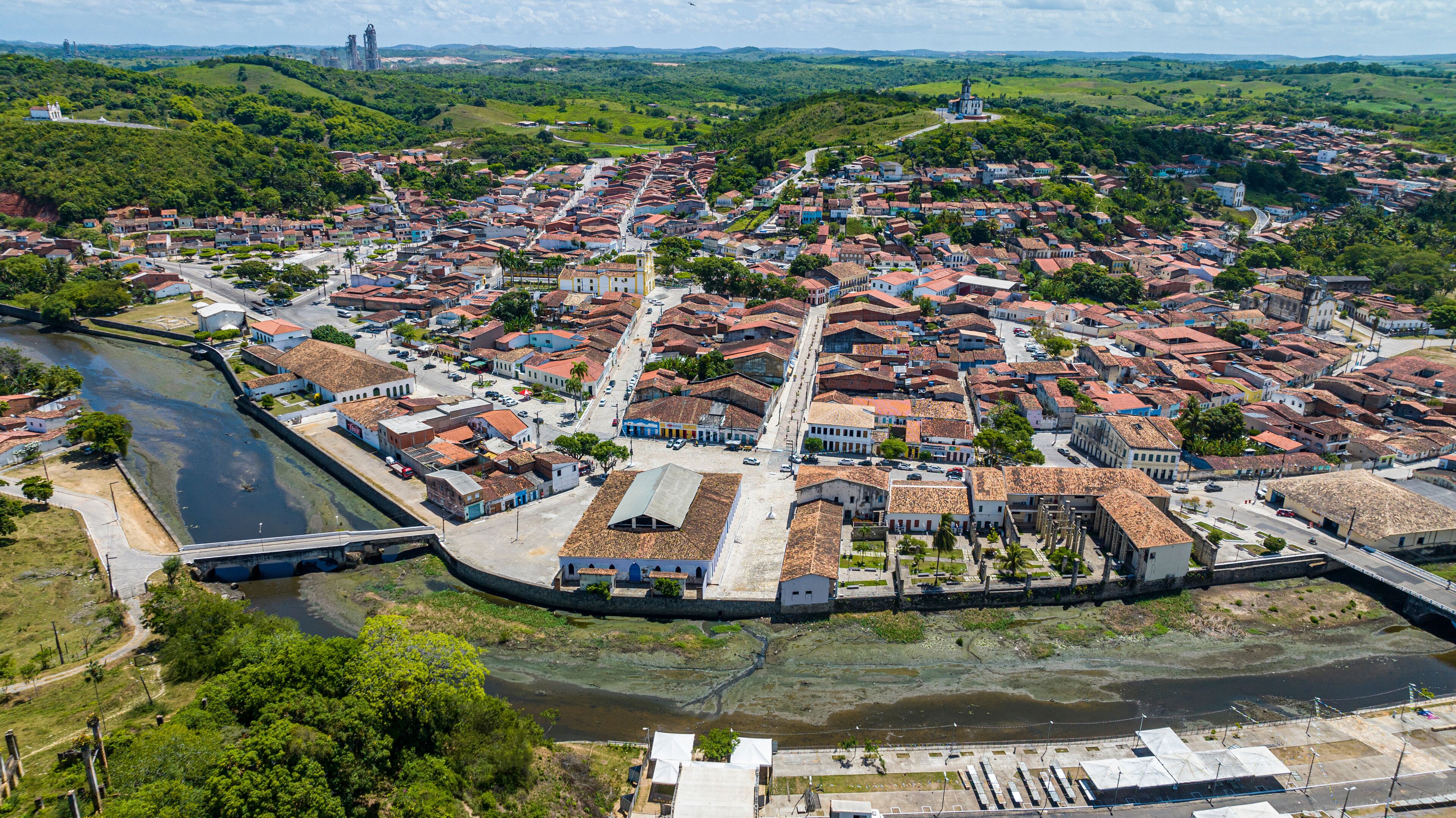 An aerial view of a historic town with a river, a fortified wall, and a prominent church.
