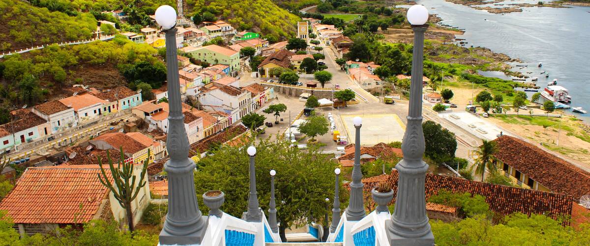 A town with colorful buildings, a river, and a staircase with street lamps.