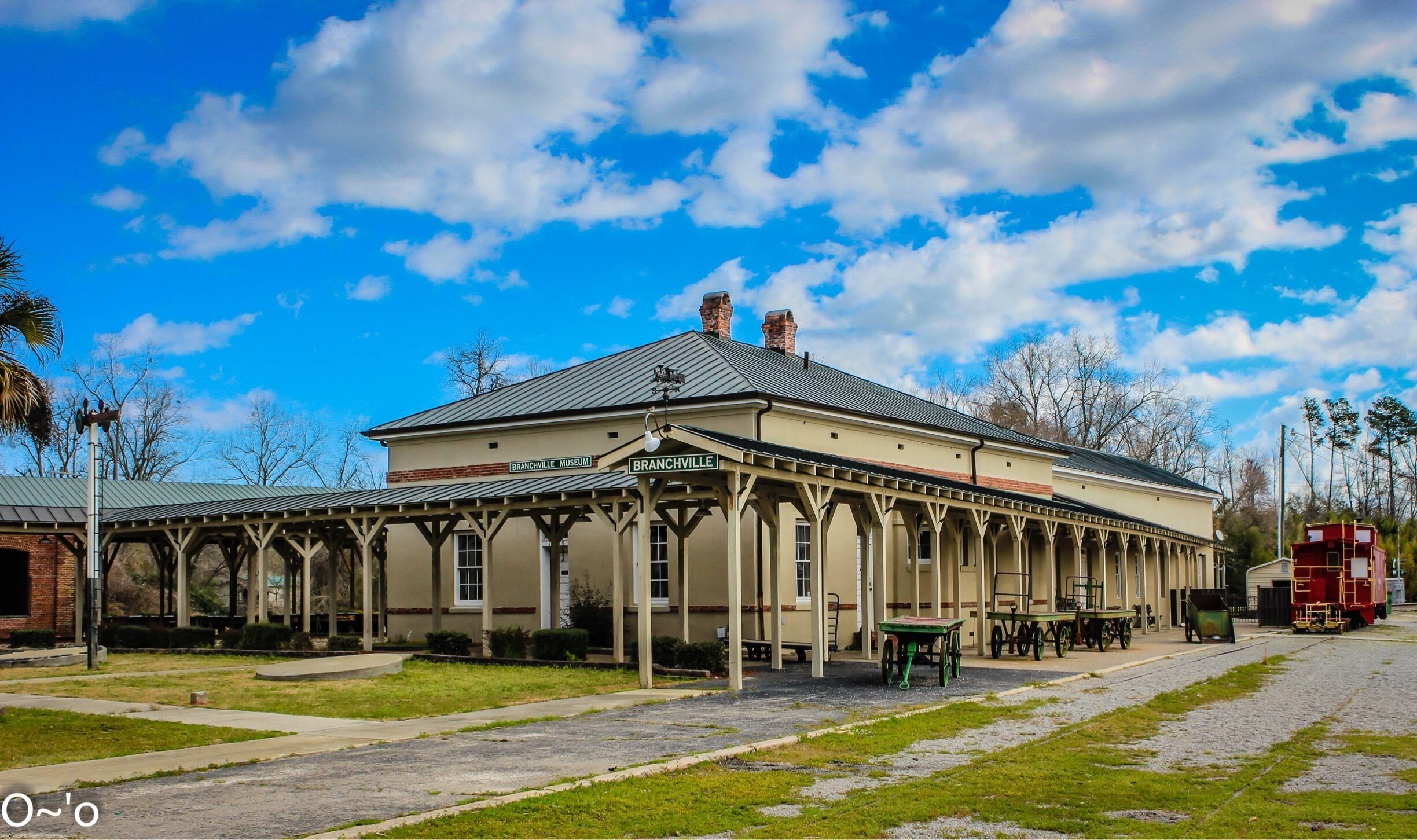 A museum with a covered walkway and a train on the tracks.