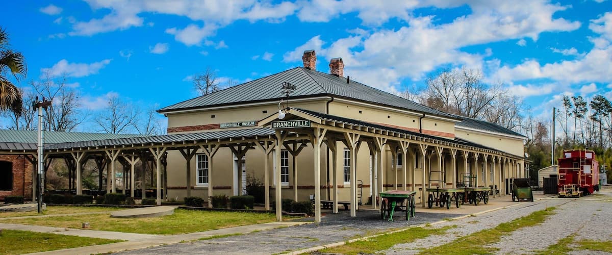 A museum with a covered walkway and a train on the tracks.