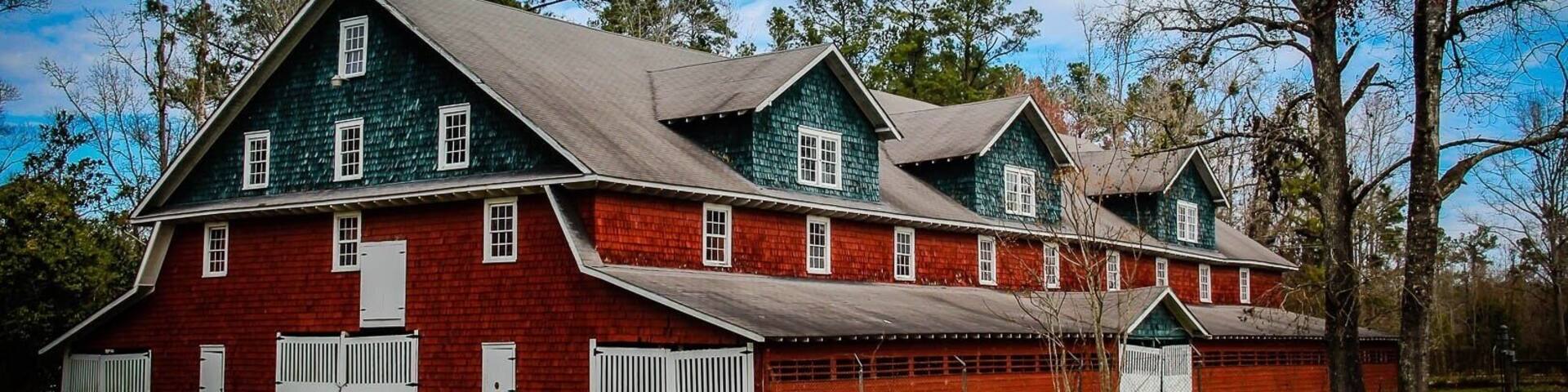Big Red Barn c. 1928
This huge three-story Dutch Colonial design barn featured an elevator as well as a three-story incline drive up ramp to utilize the third floor. In the 1930's, it housed required farm animals, mainly mules, to pull the heavy farming equipment. The original lightning rod system along the roof ridge is still intact. In 1970, the state highway department moved the location of the U.S. Highway 501 rather than cut 28 feet off the barn.